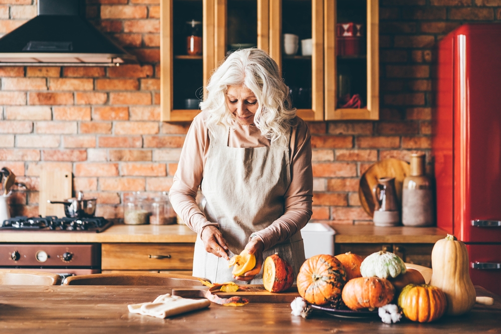 a senior woman chops up vegetables to create autumn recipes