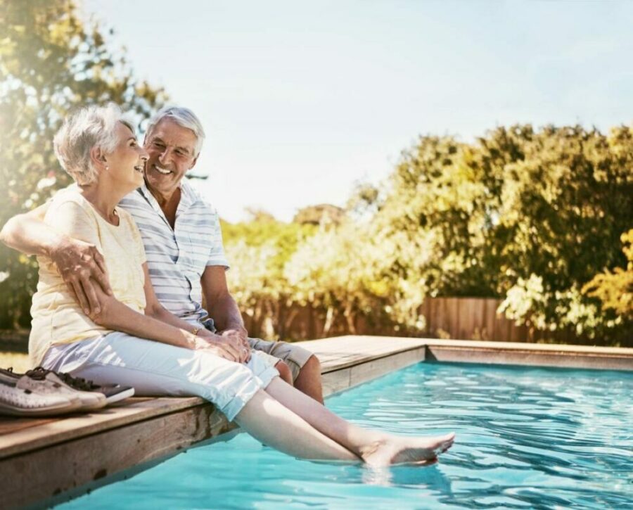 Senior couple with their feet in the pool
