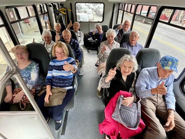 A group of people on a bus giving thumbs up.