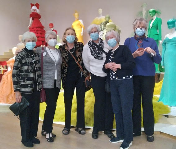 A group of women wearing face masks in front of mannequins.