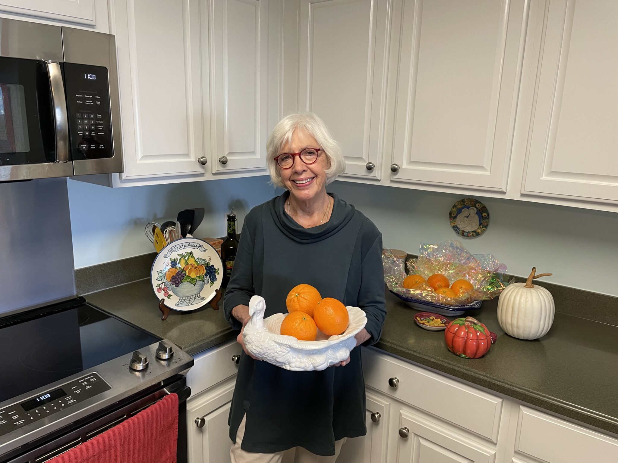 A woman holding oranges in a kitchen.