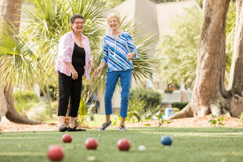 Two women playing bocce ball in a park.