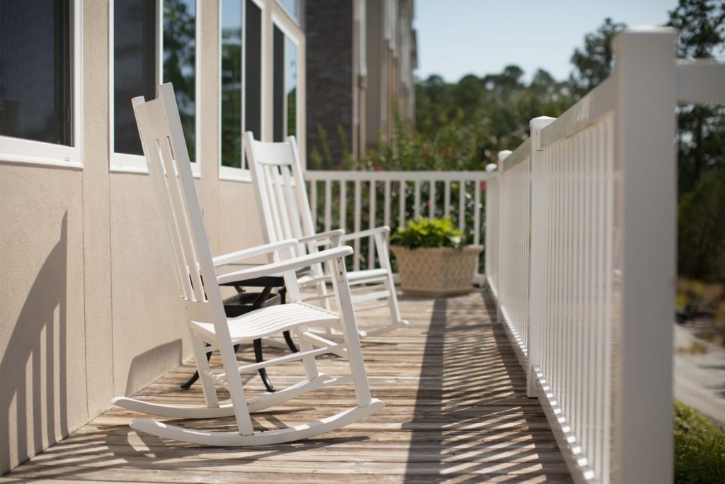 Photo of white rocking chairs outside on a wood patio