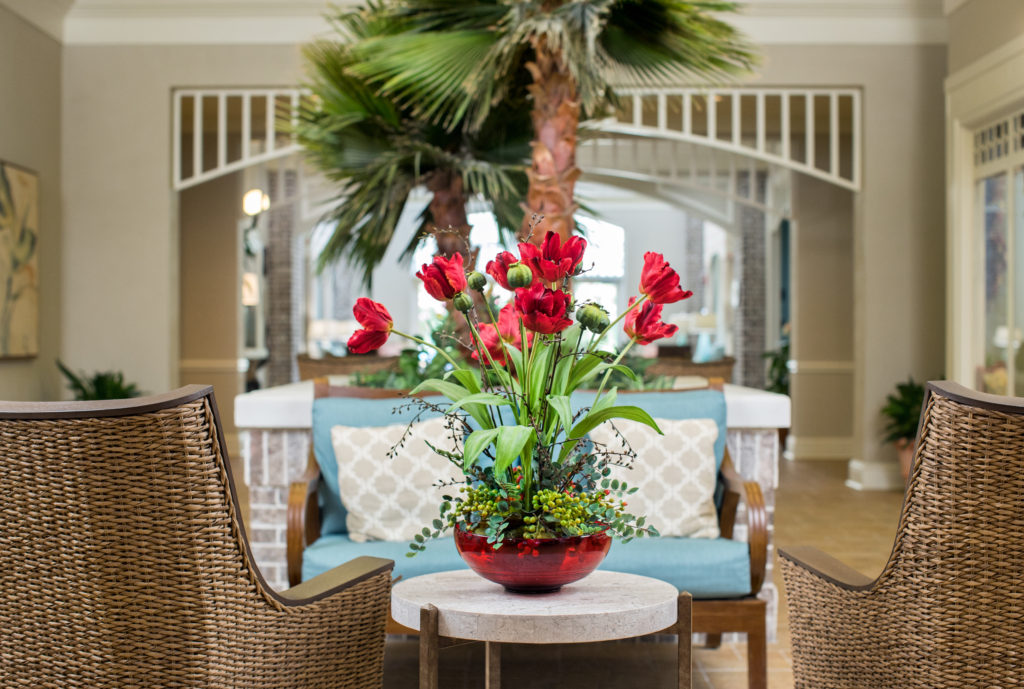A photo of a lobby with wicker furniture and flowers in the lobby