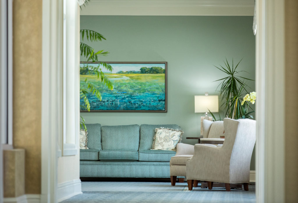 A photo of a living room with a couch and two armchairs in a sea foam green, blue, and pale grey color palette