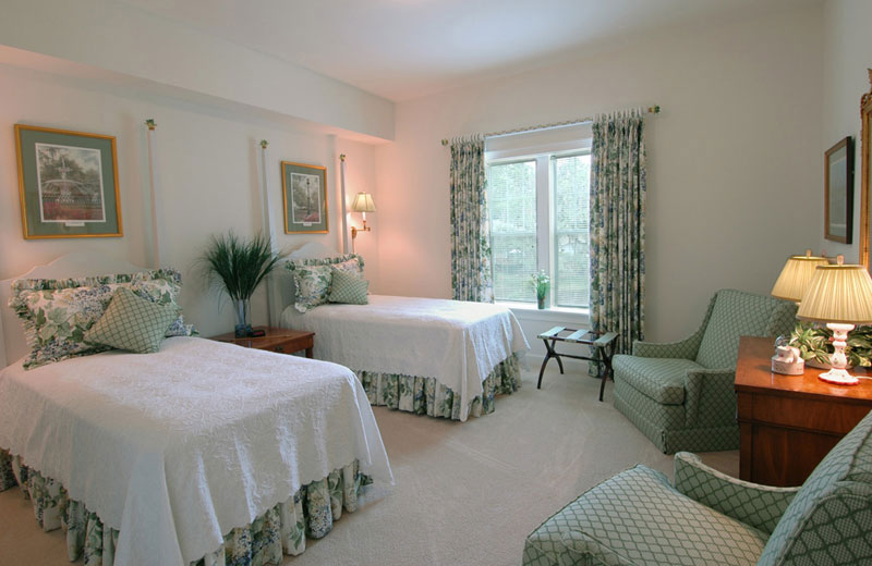 A photo of a bedroom in a senior apartment with two twin sized beds and two matching armchairs