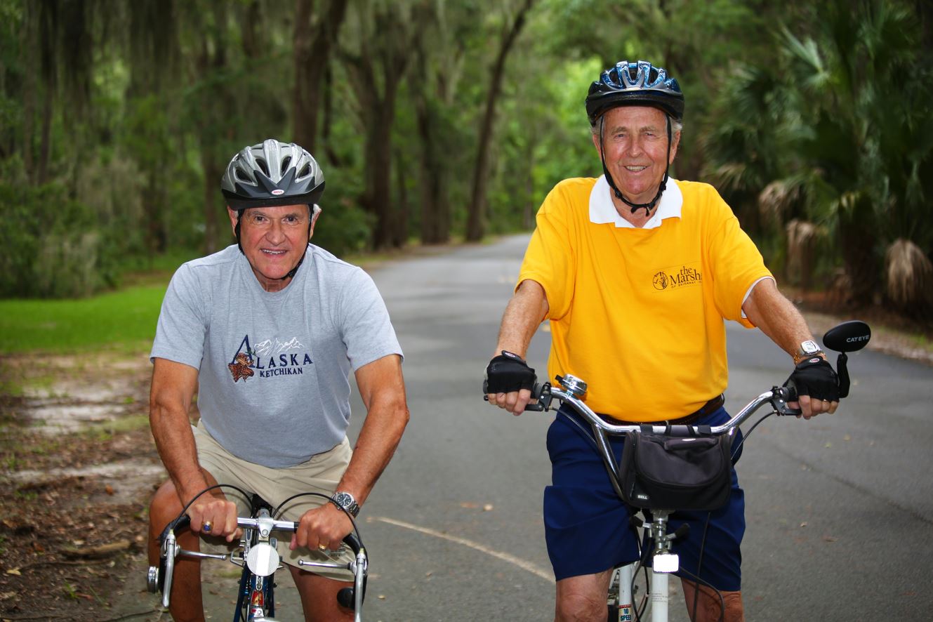 Two men riding bikes on a paved road.