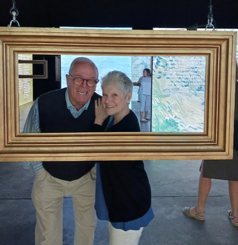 A man and woman posing in front of a large frame.