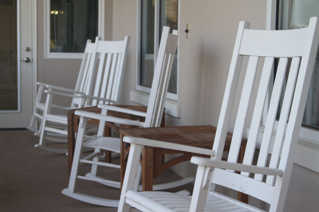 A photo of white rocking chairs outside on a deck