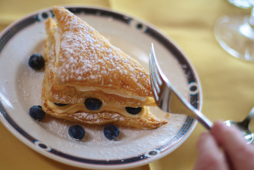 A pastry with powdered sugar and whole blueberries