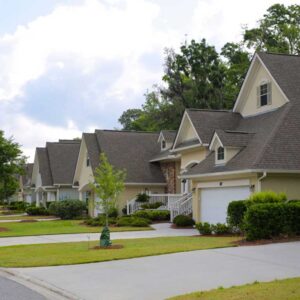 Row of cottages at The Marshes with neat lawns, trees, and overcast sky.